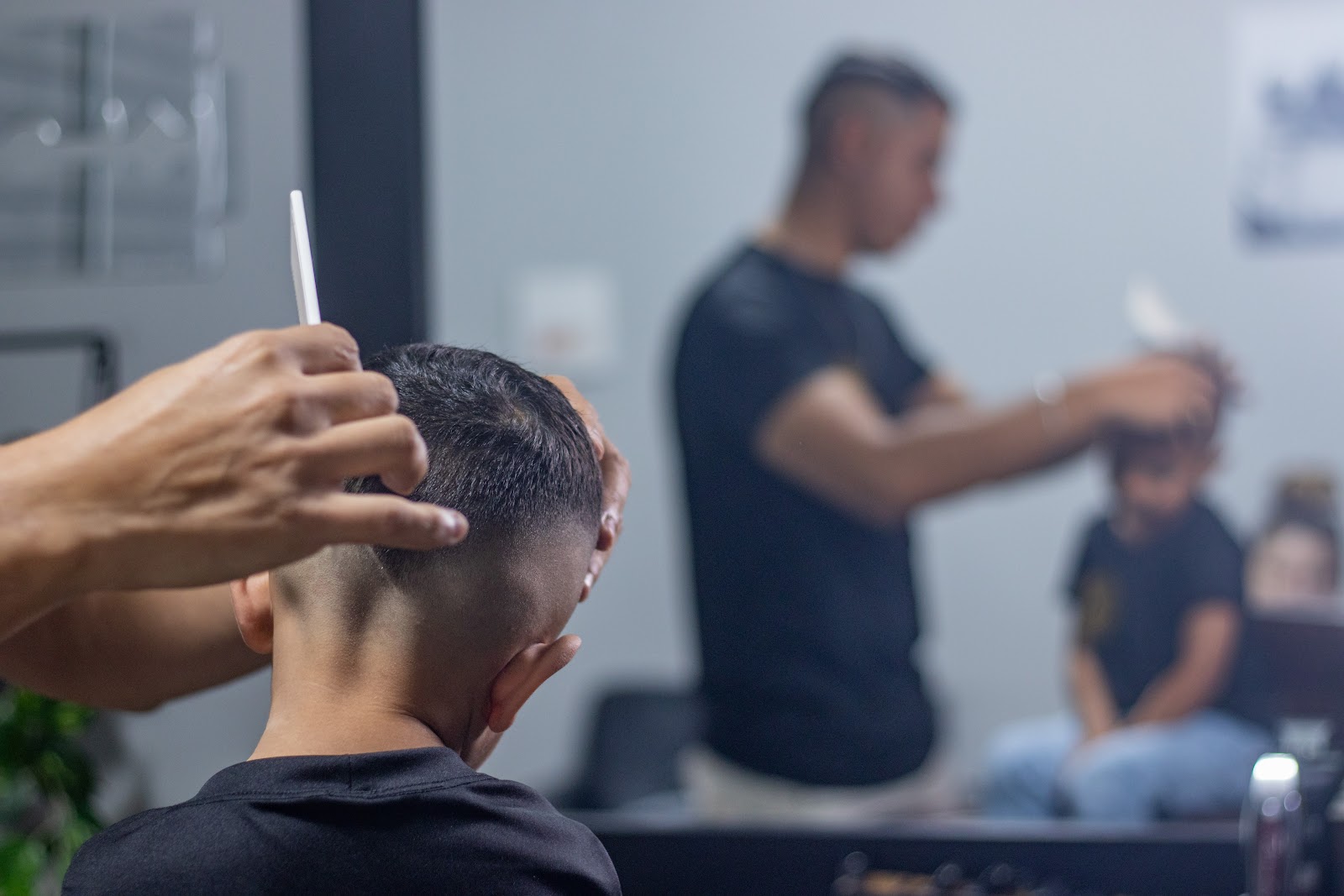Barbeiro cortando o cabelo de um cliente, refletido no espelho da Barbearia Navalha Nobre